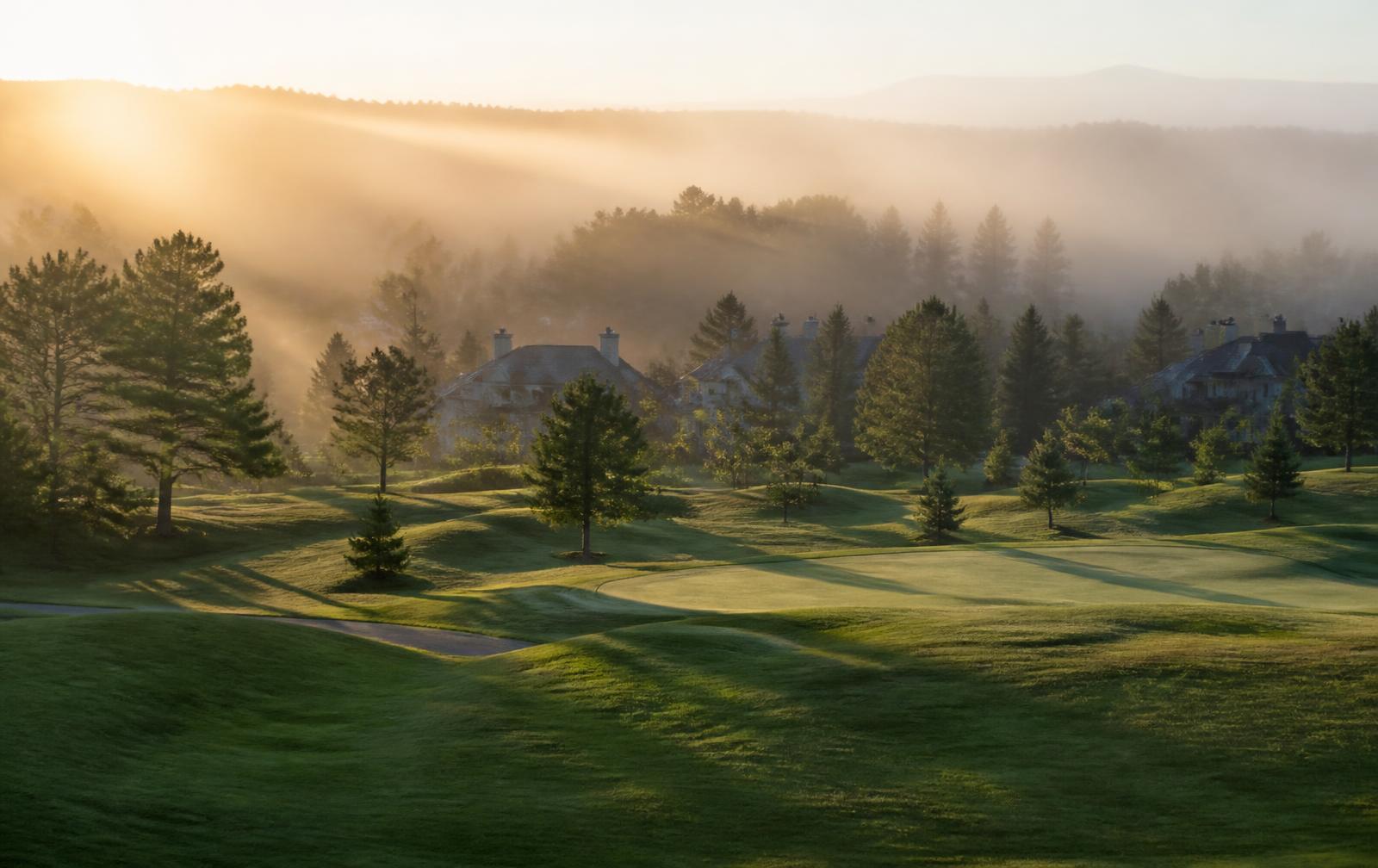Morning mist over fairways and estate rooftops near Quail Hollow